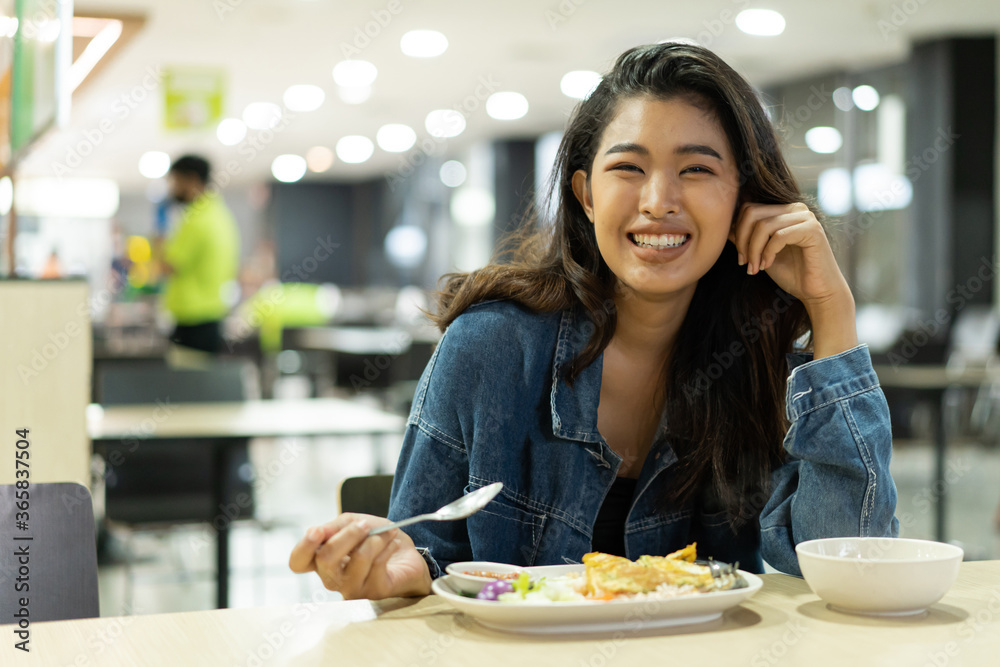 Young Asian woman looking at camera in restaurant eating meal. Beautiful Asia girl smiling in cafeteria
