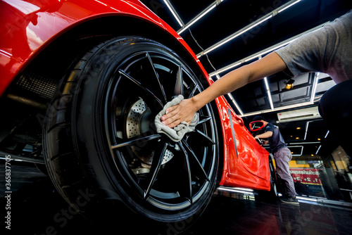 Car service worker polishing car wheels with microfiber cloth.