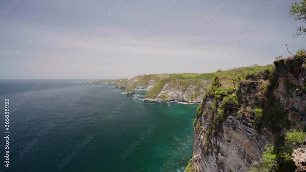 Nature landscape with mountain in sea and rocks. Amazing mountain cliff in the azure ocean water against the backdrop of beautiful tropical nature. Bali, Indonesia Nature landscape with mountain in sea and rocks. Amazing mountain cliff in the azure ocean water against the backdrop of beautiful tropical nature. Bali, Indonesia