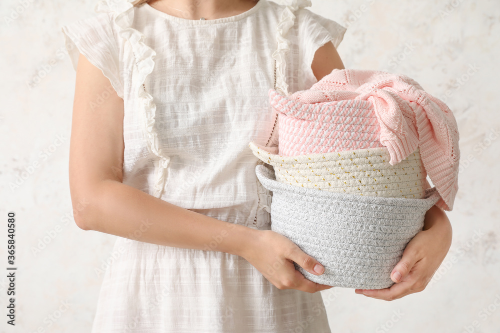 Woman holding wicker baskets with plaid on light background Woman holding wicker baskets with plaid on light background