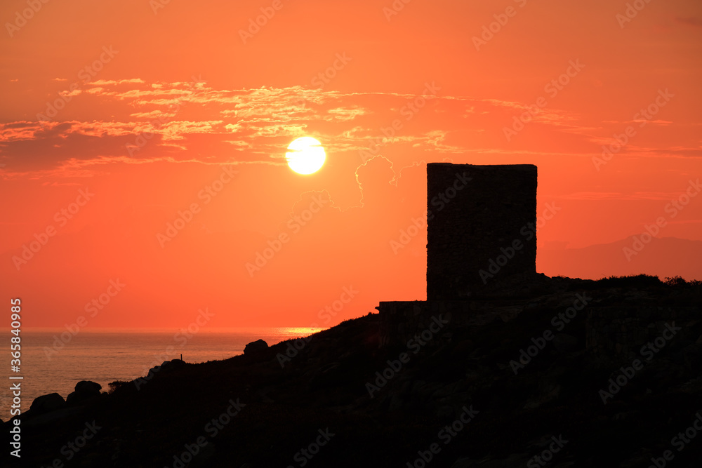 Sun rising behind genoese tower in Corsica Sun rising behind genoese tower in Corsica