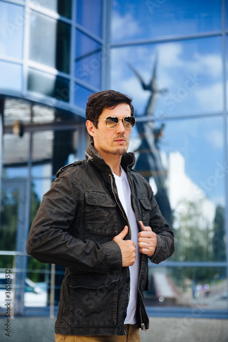 Handsome fashionable male in sunglasses adjusting casual jacket