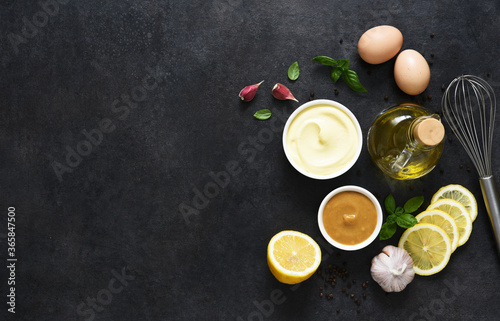 Homemade mayonnaise on a black background. Ingredients for making the sauce: egg, butter, mustard.