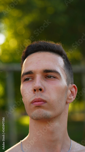 Portrait shirtless dark-haired young man with chain