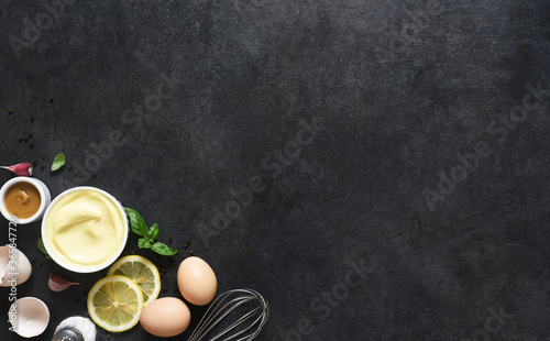 Homemade mayonnaise on a black background. Ingredients for making the sauce: egg, butter, mustard.
