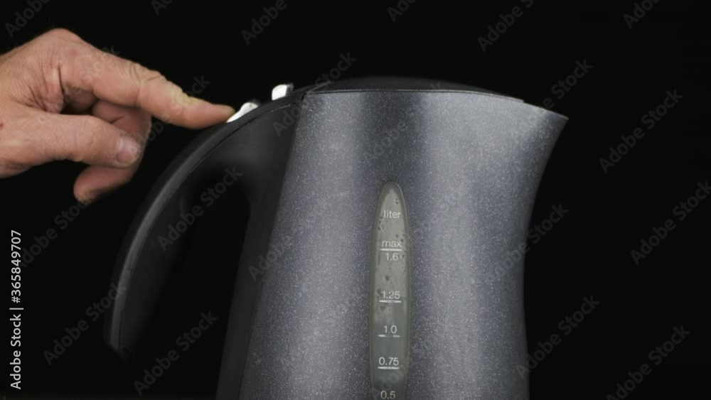 Slow motion. Person turns on the electric kettle. Boiling water and