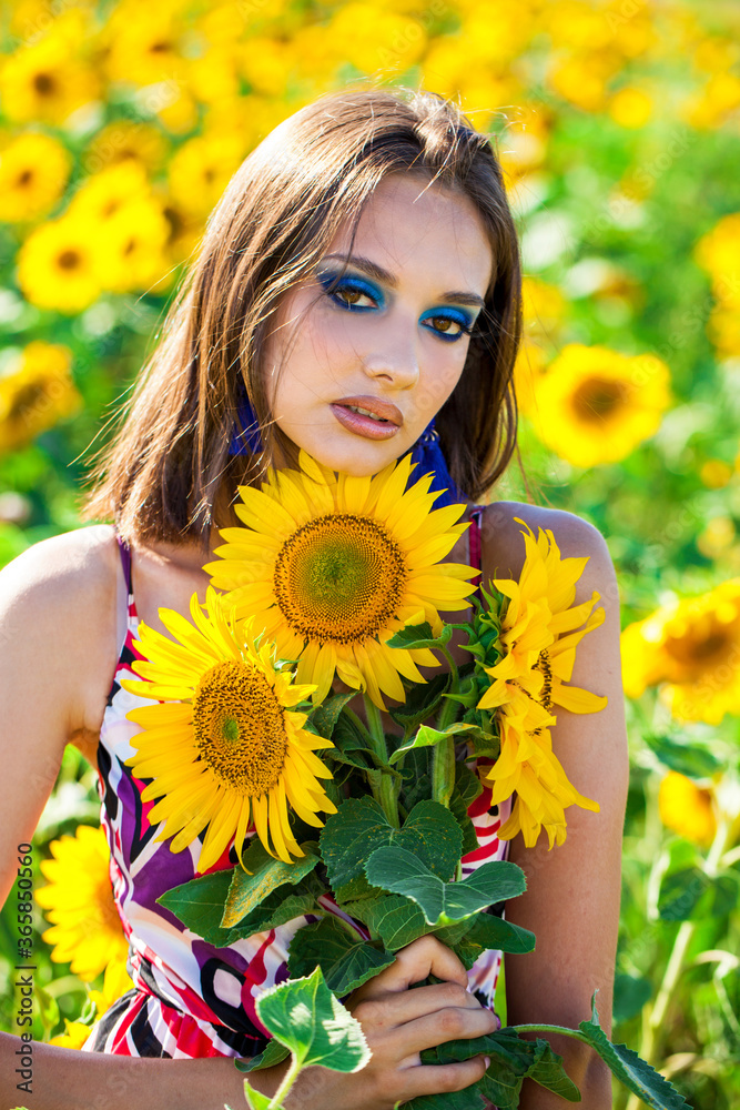 Young beautiful brunette woman with bright makeup posing in a field of sunflowers Young beautiful brunette woman with bright makeup posing in a field of sunflowers