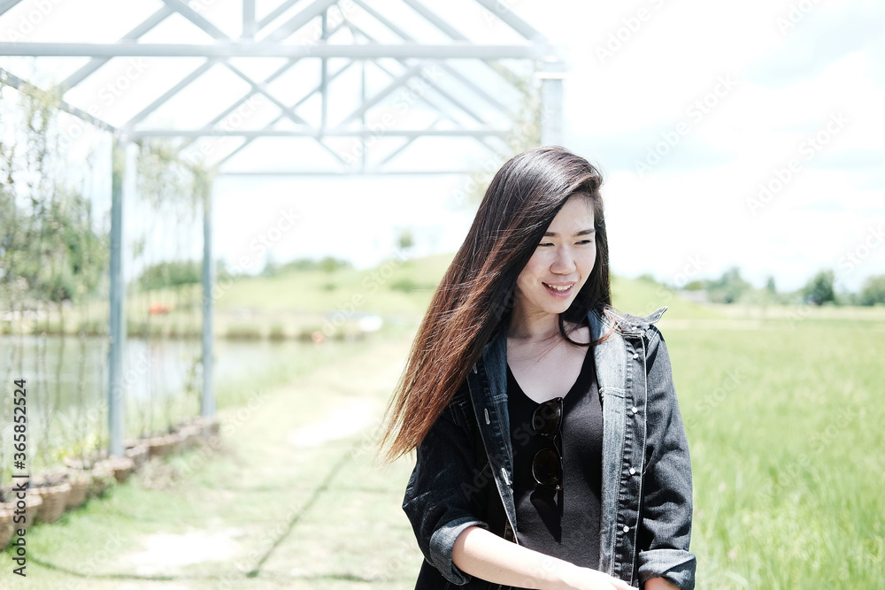 Asian sexy woman and long hair in black dress smiling in natural sunlight and wind on summer season in the park.
