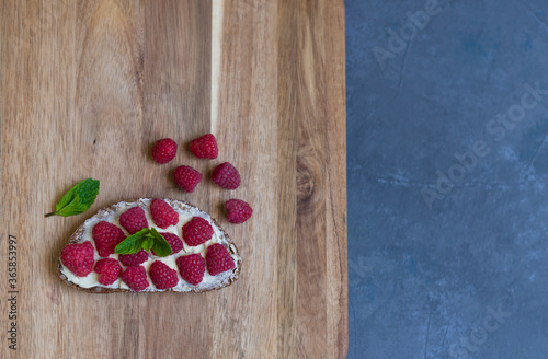 Sandwich with cream-cheese and fresh raspberries on a wooden board. Top view. Flat lay.