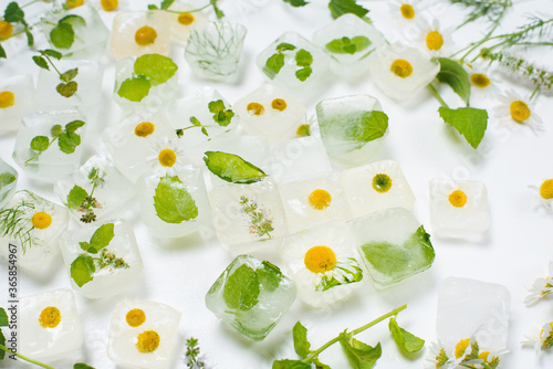 cosmetic ice cubes with chamomile and mint for home care applies to the face. The concept of skin care. cosmetics with herbs on a light background