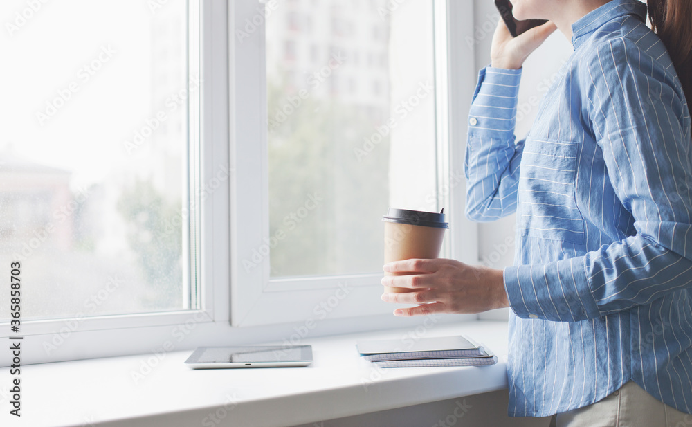 young woman talking on the phone by the window