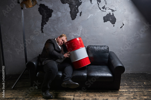 dolorous caucasian fat oilman is disappointed with price drop, he sits with oil barrels. oil production, petroleum concept photo