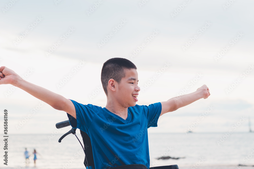 Asian special child on wheelchair smiling happily on the beach,Seaside nature background with day light, Life in the education age of disabled children, Boy have outdoor activities like normal people. Asian special child on wheelchair smiling happily on the beach,Seaside nature background with day light, Life in the education age of disabled children, Boy have outdoor activities like normal people.