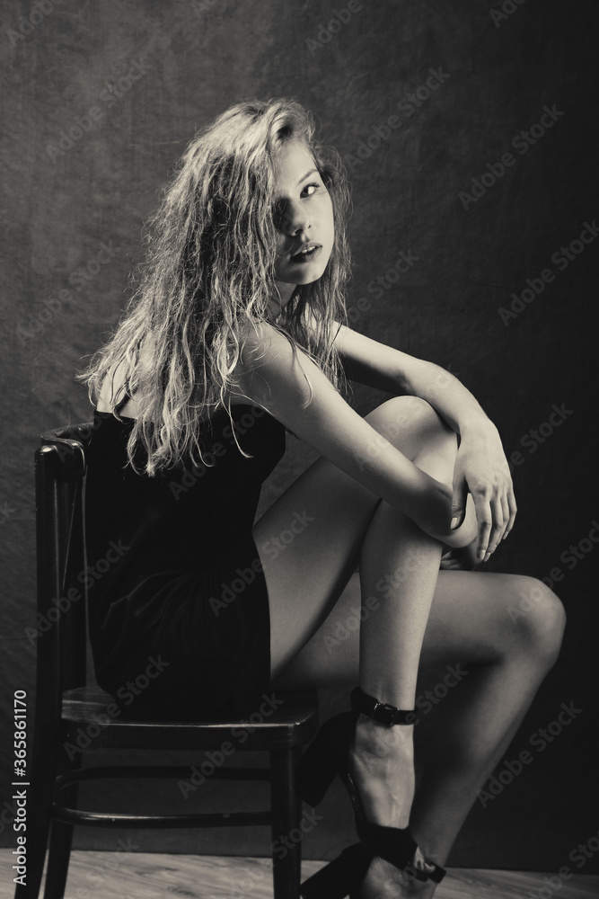 beautiful girl with wet curly hair is bent over in chair bending over ...