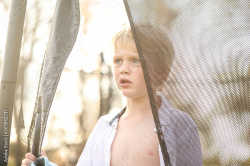 Young boy standing on trampoline with white shirt unbuttoned photo