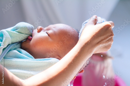 Asian Mother give a bath her newborn baby, Mother is washing baby hair