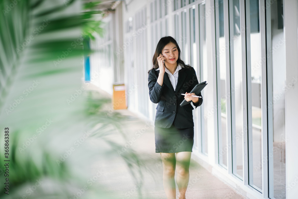 Beautiful asian business woman talking on cellphone while walking outdoor