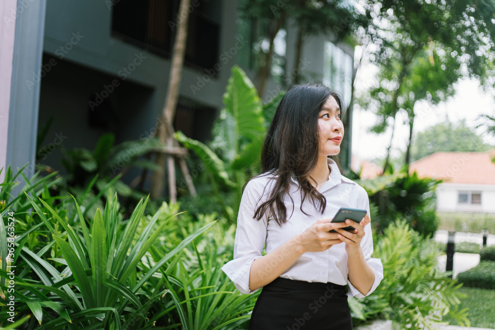 Naklejka premium Beautiful asian business woman using on smartphone while walking outdoor
