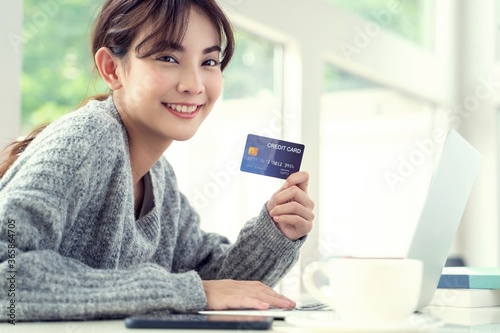 Young Asian Woman Smiling To Camera With Credit Card In Hand.