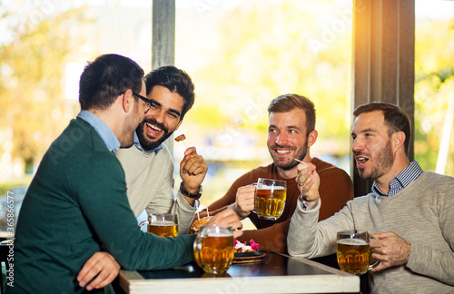 Friends talking and drinking beer in pub