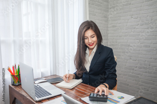 Beautiful businesswoman or financial manager working in modern office on a laptop.