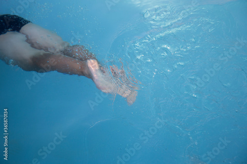 A young man swimming under the water in home swimming pool. Summer sport at home. Garden swimming pool. 