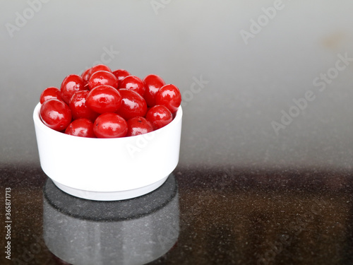 Fototapeta Naklejka Na Ścianę i Meble -  Red color cherry fruits in a white bowl against dark background, with copy space, caption