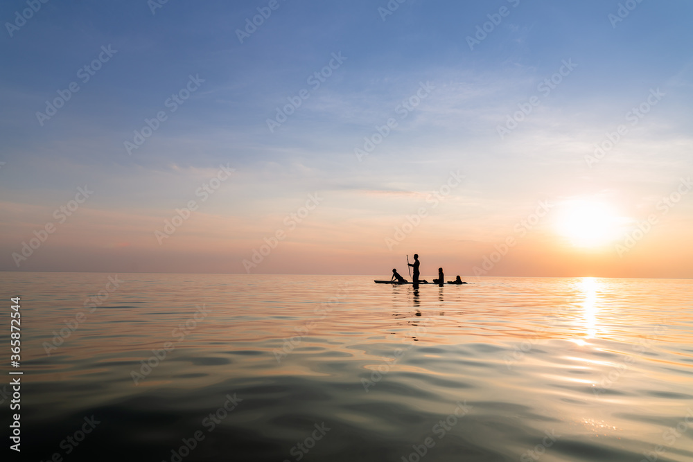 Silhouette of father and children on paddle board at sunset on lake michigan Silhouette of father and children on paddle board at sunset on lake michigan