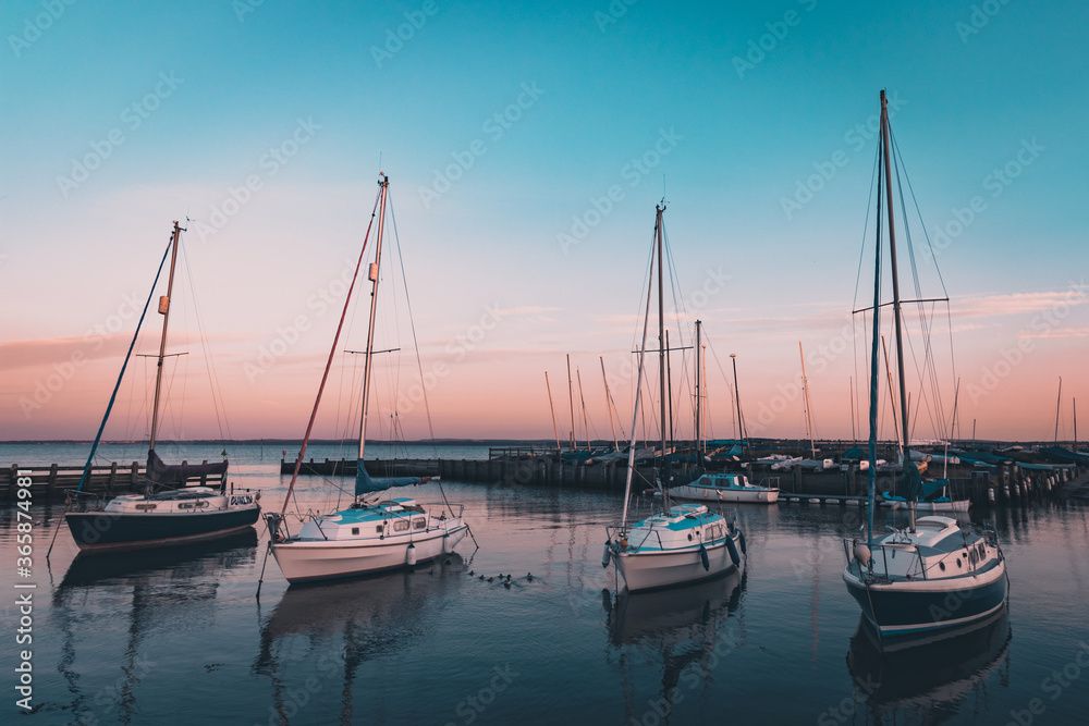 Four yachts in a calm harbour at sunset
