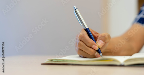 close up senior woman using pen to writing on notebook diary to planning about pension life and investment or daily activity at home for mature health and lifestyle in relax time concept