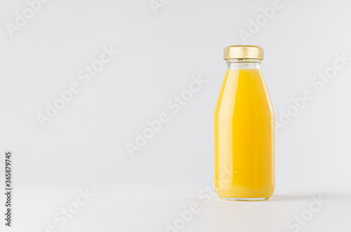 Orange yellow juice in glass bottle with gold cap mock up on white background with copy space, template for packaging, advertising, design product, branding.
