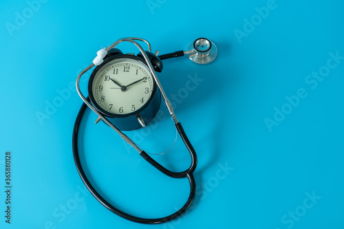 Stethoscope and vintage clock on blue background. Medical and health care concept © littlestocker