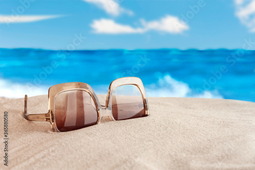 Fototapeta Naklejka Na Ścianę i Meble -  Sunglasses on the seashore, tropical beach vacation background .