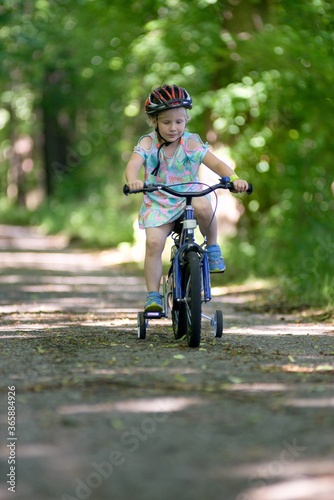 Fototapeta Naklejka Na Ścianę i Meble -  The first bike ride a little girl learns to ride a bicycle.