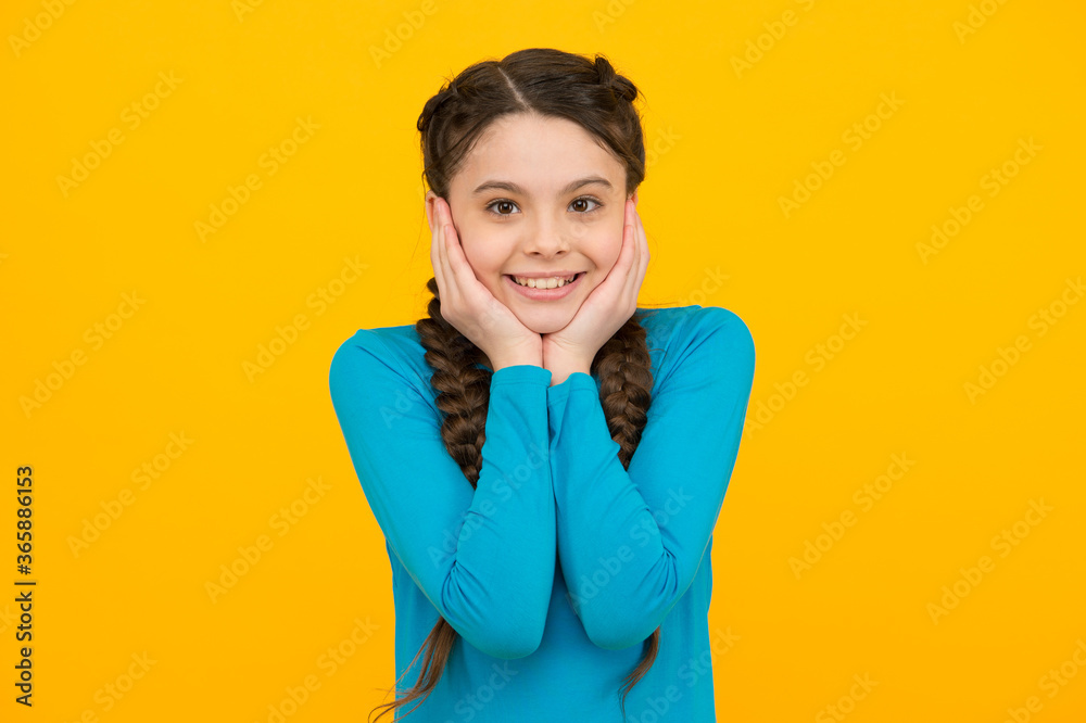 smiling child with long hairdo. cheerful teen with healthy smile. Hair braided in braids. little beauty pleasantly surprised. happy childhood. small girl has nice smile. kid hairstyle fashion