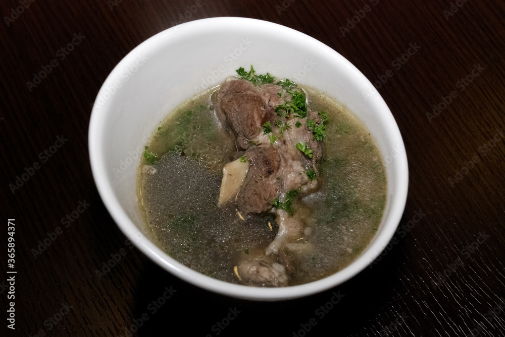 meat in the broth with some herbs served in the white bowl meat in the broth with some herbs served in the white bowl