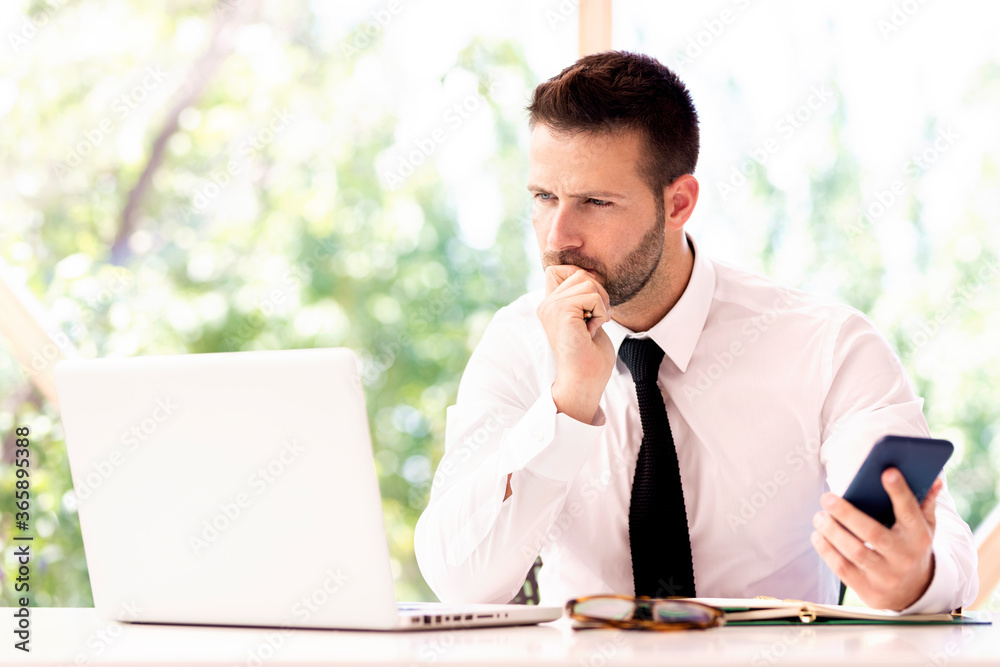 Handsome businessman working on laptop at office desk Handsome businessman working on laptop at office desk