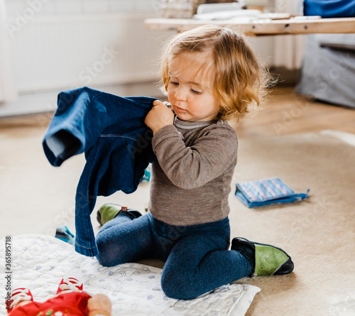 Toddler girl getting dressed in living room