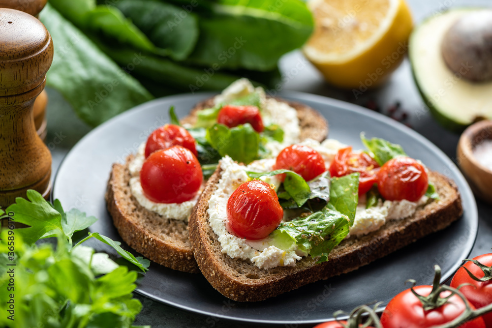 Tasty sandwich with soft white ricotta cheese, roasted tomatoes and basil garnished with crushed pepper and olive oil