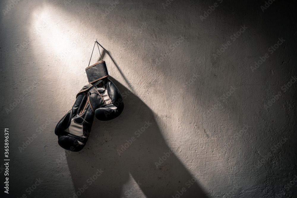 Guantes de boxeo negros colgados en una pared blanca desgastada con  textura, iluminados por un flash duro que genera un haz de luz diagonal  foto de Stock | Adobe Stock