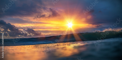 Sunset sea tropical background, surfing wave incoming with surfers on ocean water surface