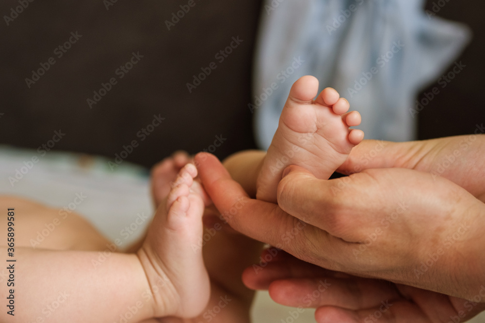 Little feet of the kid in the male hands of the dad Little feet of the kid in the male hands of the dad