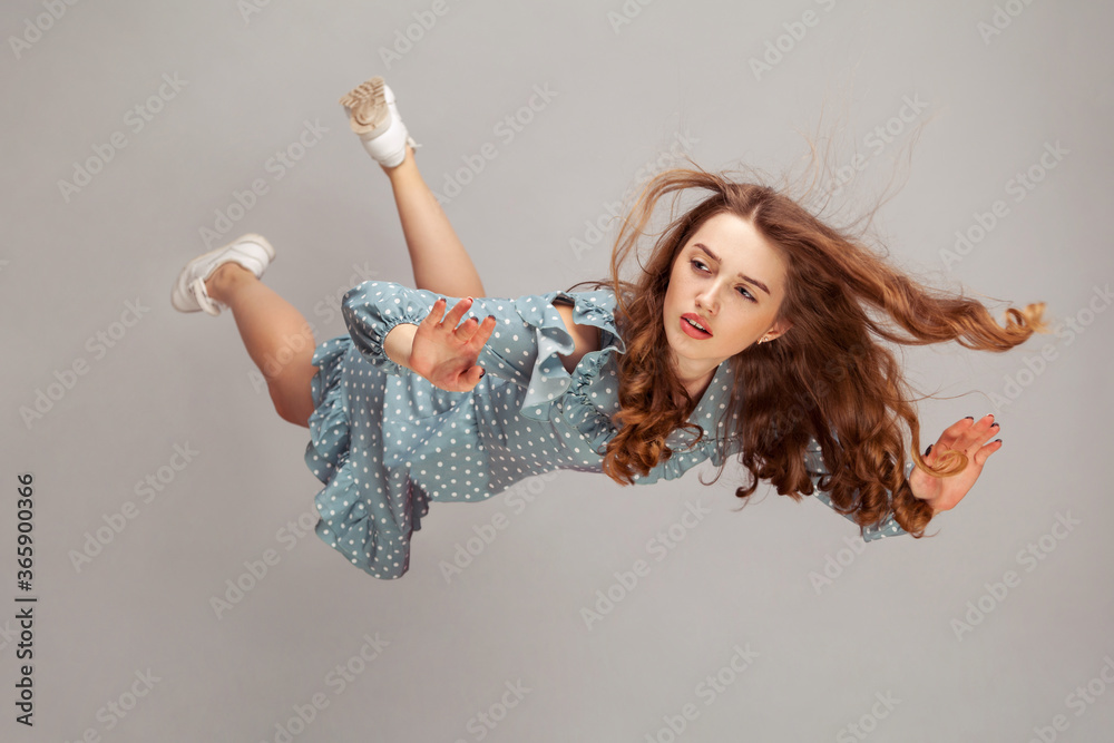 Tableau sur toile Beautiful girl levitating in mid-air, falling down and her hair messed up soaring from wind, model flying hovering with dreamy peaceful expression