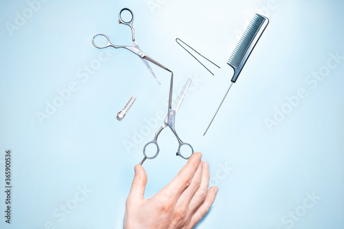 Had holding flying hairdresser tools comb, scissors under trendy color background with copy space and soft light. Stylish Professional Barber Scissors, Hairdresser salon concept, Haircut accessories.