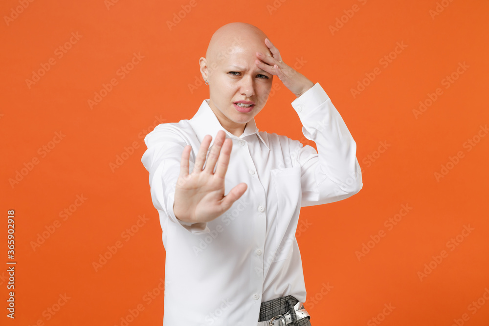 Displeased young bald business woman in white shirt isolated on orange background. Achievement career wealth business concept. Mock up copy space. Showing stop gesture with palm, put hand on head. Displeased young bald business woman in white shirt isolated on orange background. Achievement career wealth business concept. Mock up copy space. Showing stop gesture with palm, put hand on head.