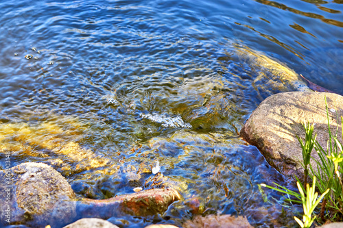 Water ripples on the shore over stones in a lake.