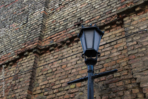 Old-fashioned street lantern in front of the old brick wall.