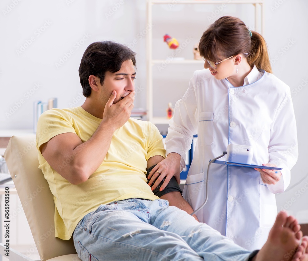 Fototapeta premium Young doctor checking patients blood pressure