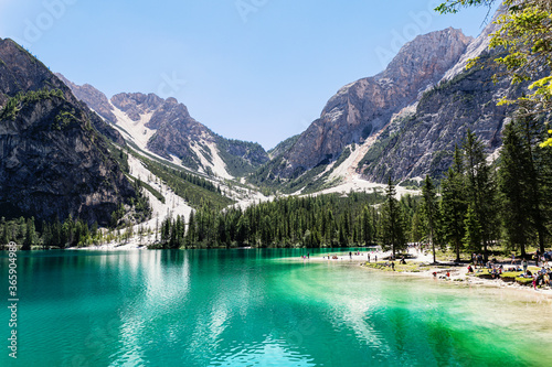 Braies Lake in the mountains, in the Italian Alps, Dolomites. Bright colors, blue and green, crystal clear water, mountains that are reflected on the lake, clean air and blue sky. woods with tall tree