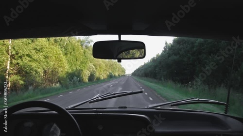 An old retro unic car driving slowly on a bumpy and narrow highway, interior view of the dashboard photo